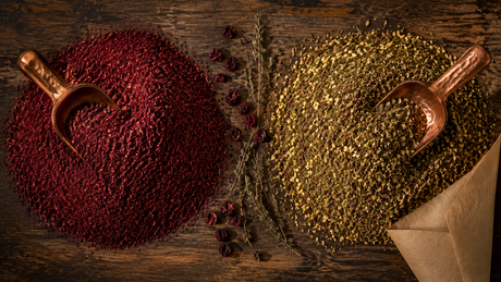 Mounds of deep red ground sumac and green-brown zaatar blend side by side on a Turkish spice counter